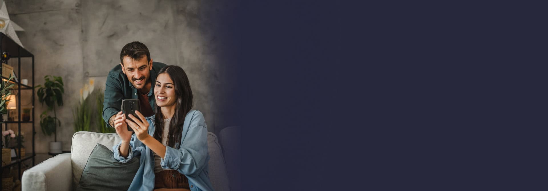 Happy couple reviewing crypto loan details on a mobile phone at home.